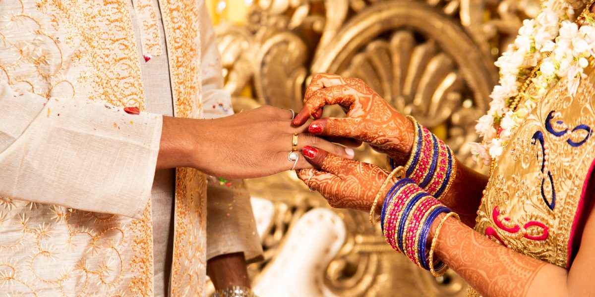 Groom putting a ring on bride's finger during indian ring ceremony