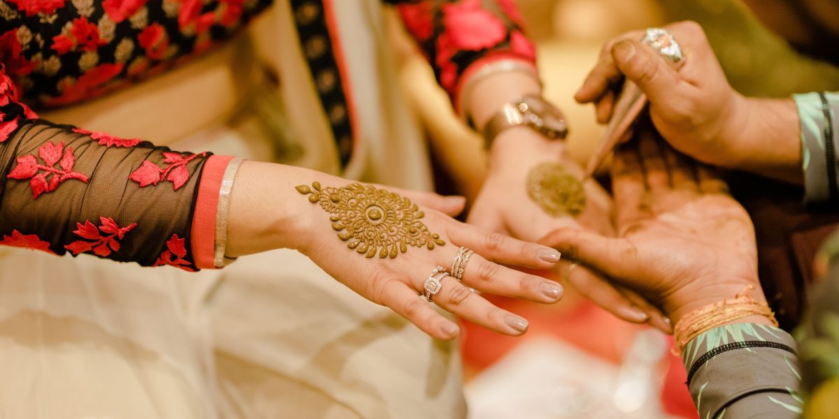 Woman having her hands tattooed with henna during a traditional Indian wedding